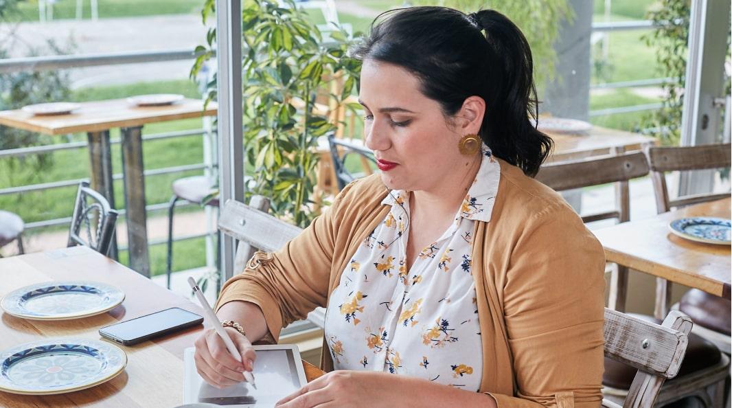 Senior Full Stack Engineer Mayra Rodriguez taking notes on tablet with electronic pencil at the restaurant