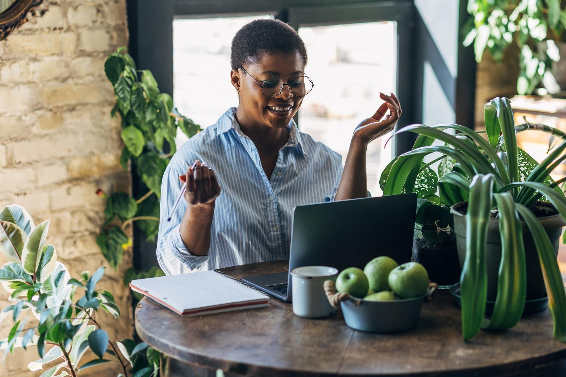 woman looking animated in front of a laptop, surrounded by plants